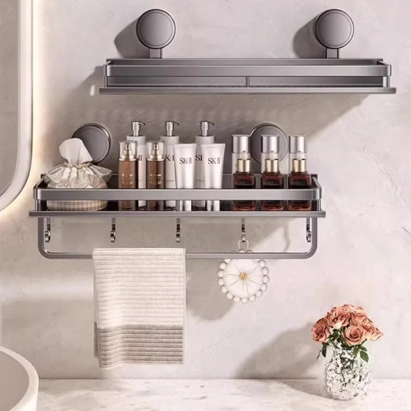 A wall-mounted shower caddy with suction cups holds various skincare bottles and a white towel on a gray wall.