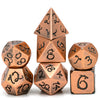A set of seven metal polyhedral dice with a dragon font design arranged in a pyramid and surrounding dice.