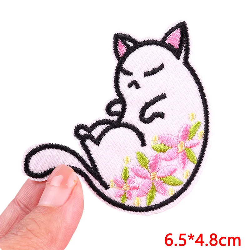 Pink and black embroidered patch of a sleeping cat with pink flowers