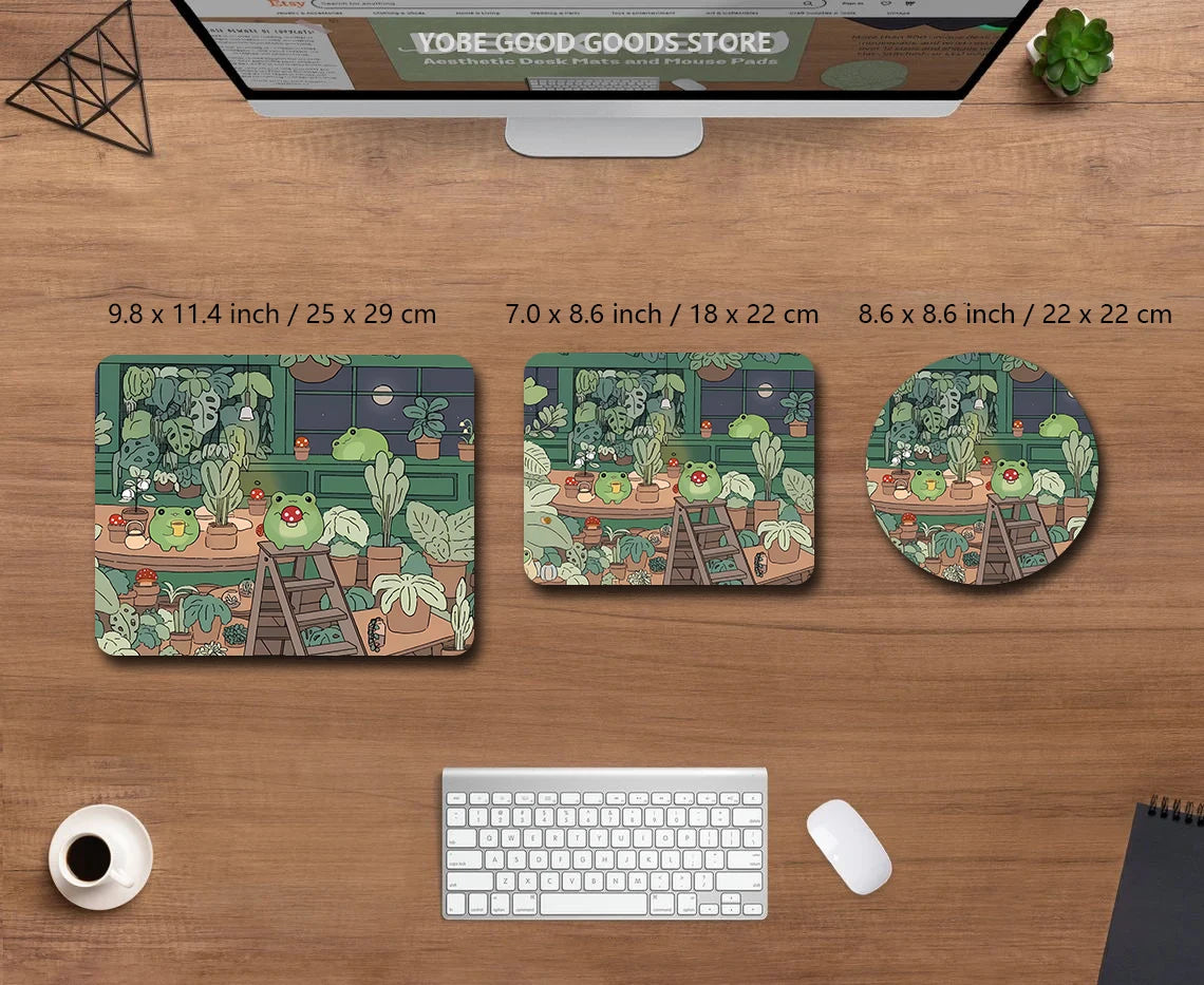 A set of three nature-themed desk mats featuring frogs and plants, displayed on a wooden desk with a laptop.