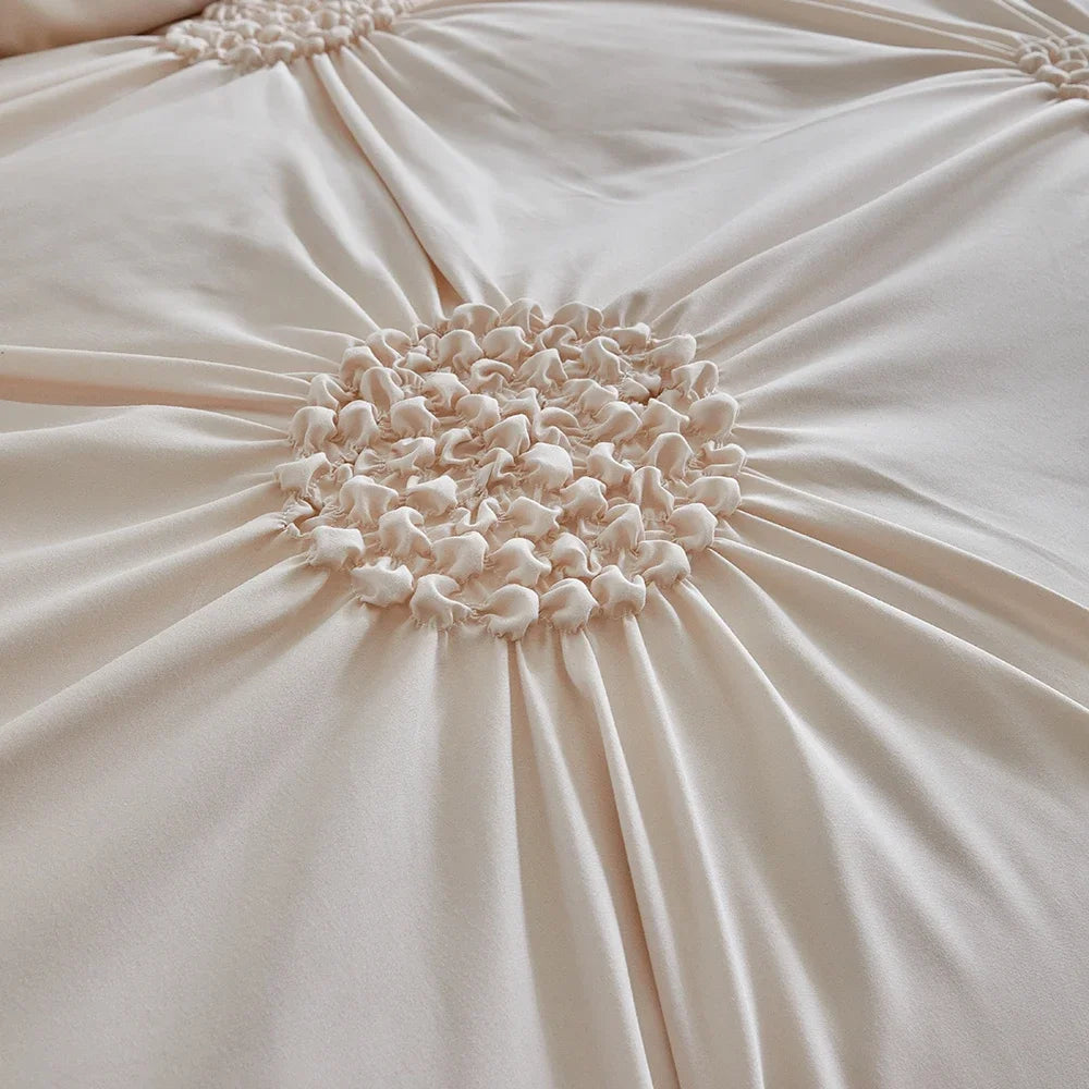 A close-up of a beige pleated duvet cover featuring a three-dimensional floral rosette detail.