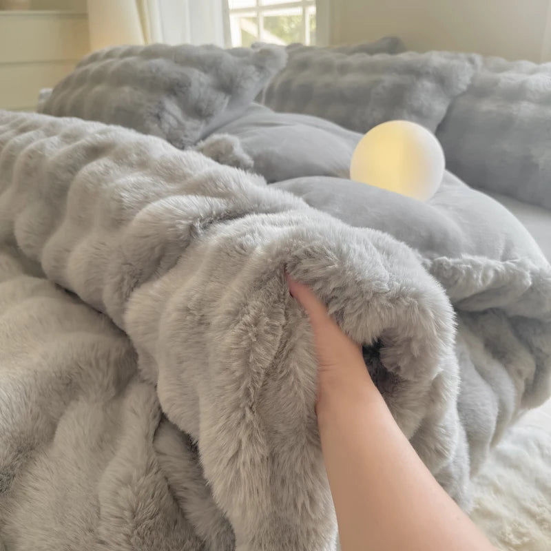 A hand is touching a fluffy gray fleece duvet cover with a rabbit design in a bright room.