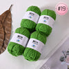 A stack of bright green Milk Cotton yarn balls with white labels on a white background.