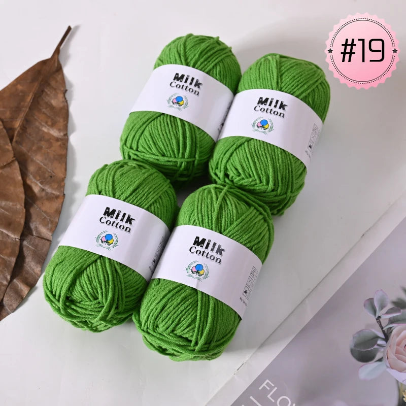 A stack of bright green Milk Cotton yarn balls with white labels on a white background.