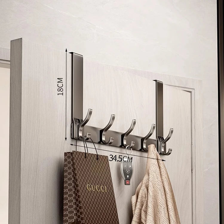A silver over-the-door organizer rack with eight hooks mounted on a white door, used for hanging items like bags and coats.