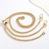 A gold-colored metal chain strap for handbags and purses, shown coiled and stretched out.