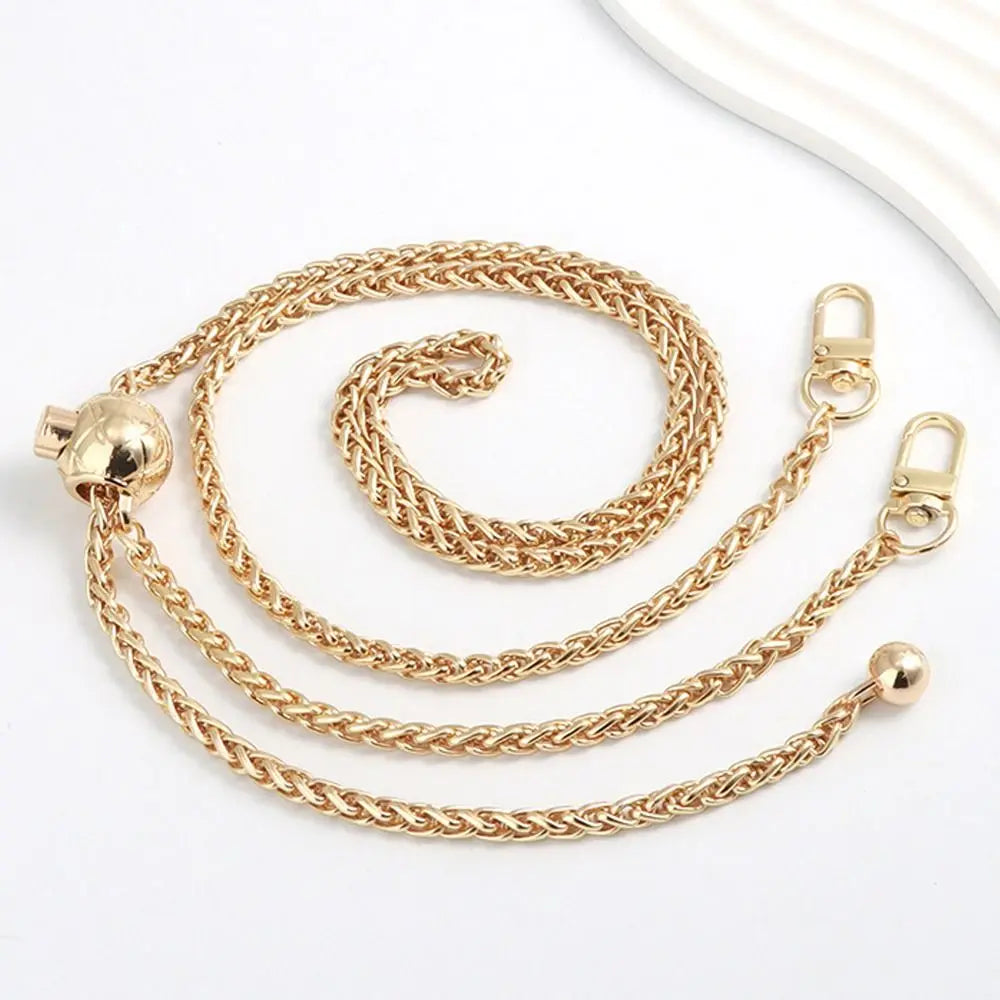 A gold-colored metal chain strap for handbags and purses, shown coiled and stretched out.