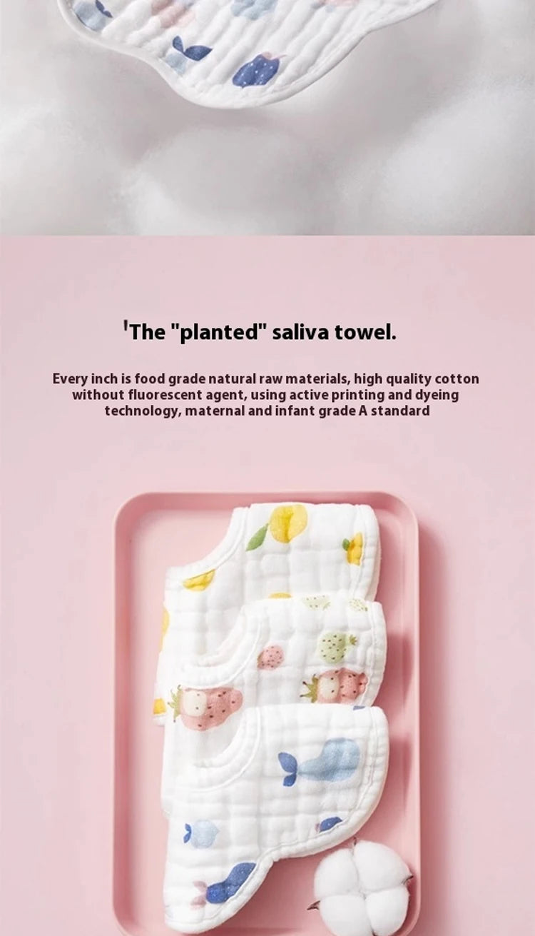 A pink tray displays a stack of white cotton muslin bandana bibs with colorful fruit and floral prints.