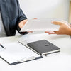 Hands are holding white padded bubble mailers with self-seal closures on a white table.