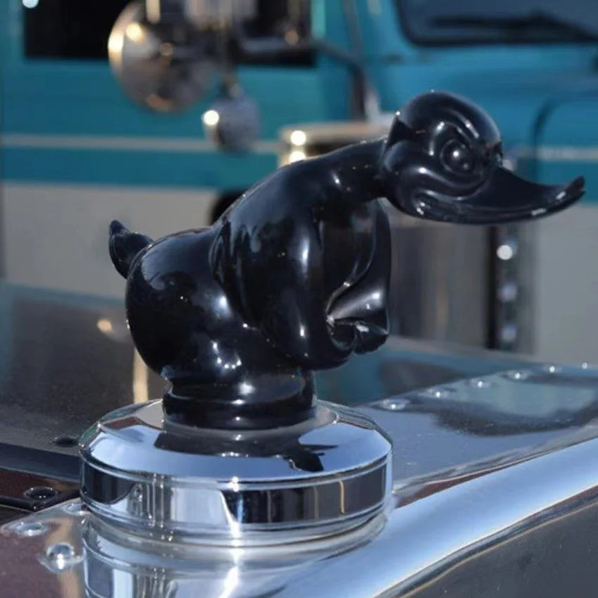 Black resin angry duck hood ornament displayed on a reflective surface.