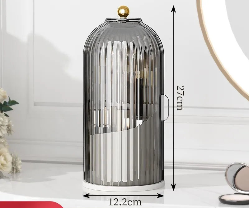 Organizador cilíndrico de vidrio para pinceles de maquillaje con tapa dorada y base blanca.