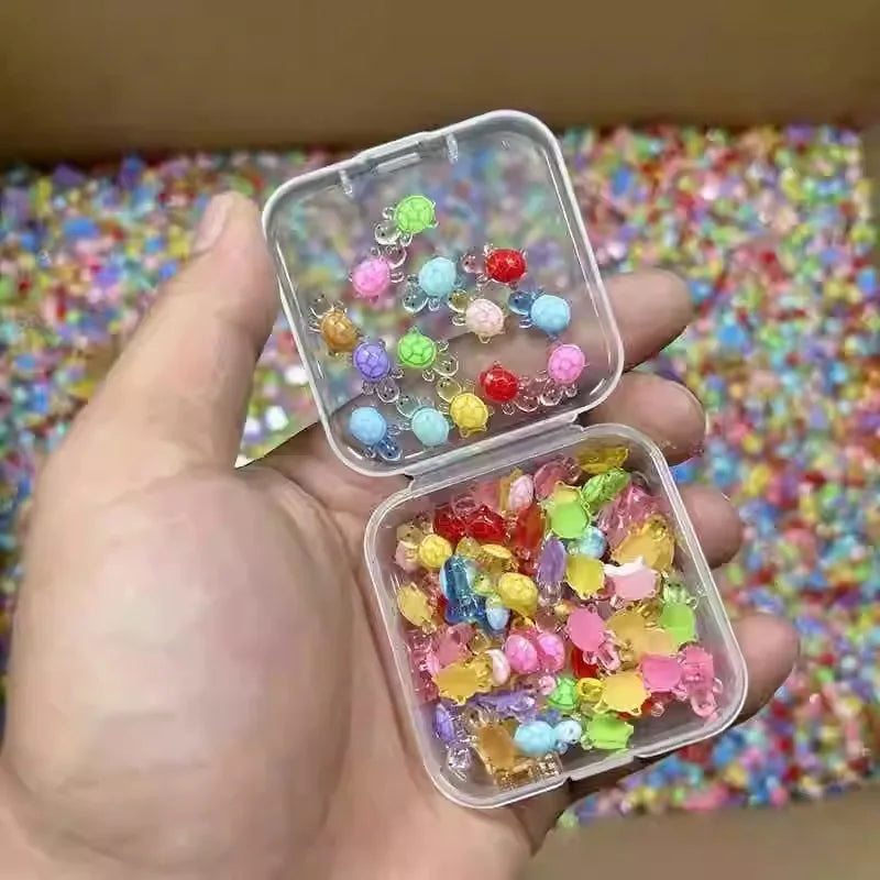 A hand holds an open clear plastic container filled with glow-in-the-dark mini turtle figurines.