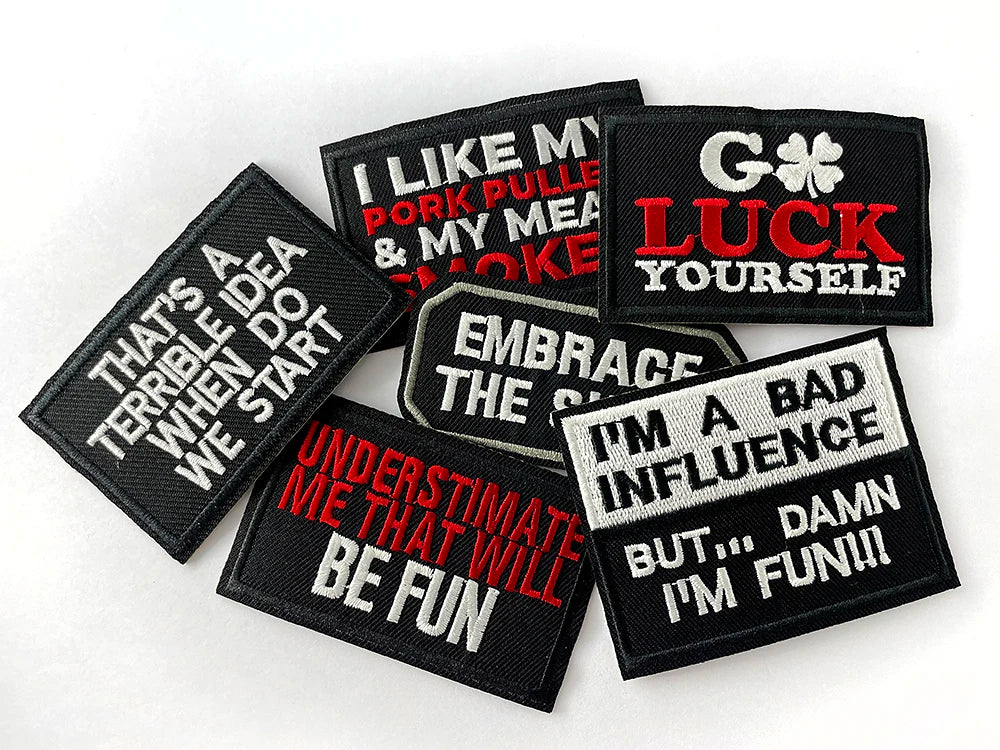 A collection of black embroidered iron-on patches with funny text such as I like my pork puddle and luck yourself