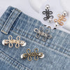 Gold and silver clover-shaped adjustable buckle for tightening waistbands on denim pants