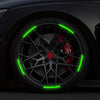 Close-up of a black car wheel with bright green reflective stickers on the rim.