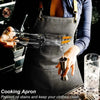 A person wearing a dark gray professional cooking apron with leather straps is pouring liquid from a bottle into a metal cup.