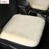 A white plush rabbit fur car seat cushion is shown inside a black car seat.