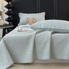 Light blue floral quilted bedspread with a fluffy pink toy resting on the bedding.