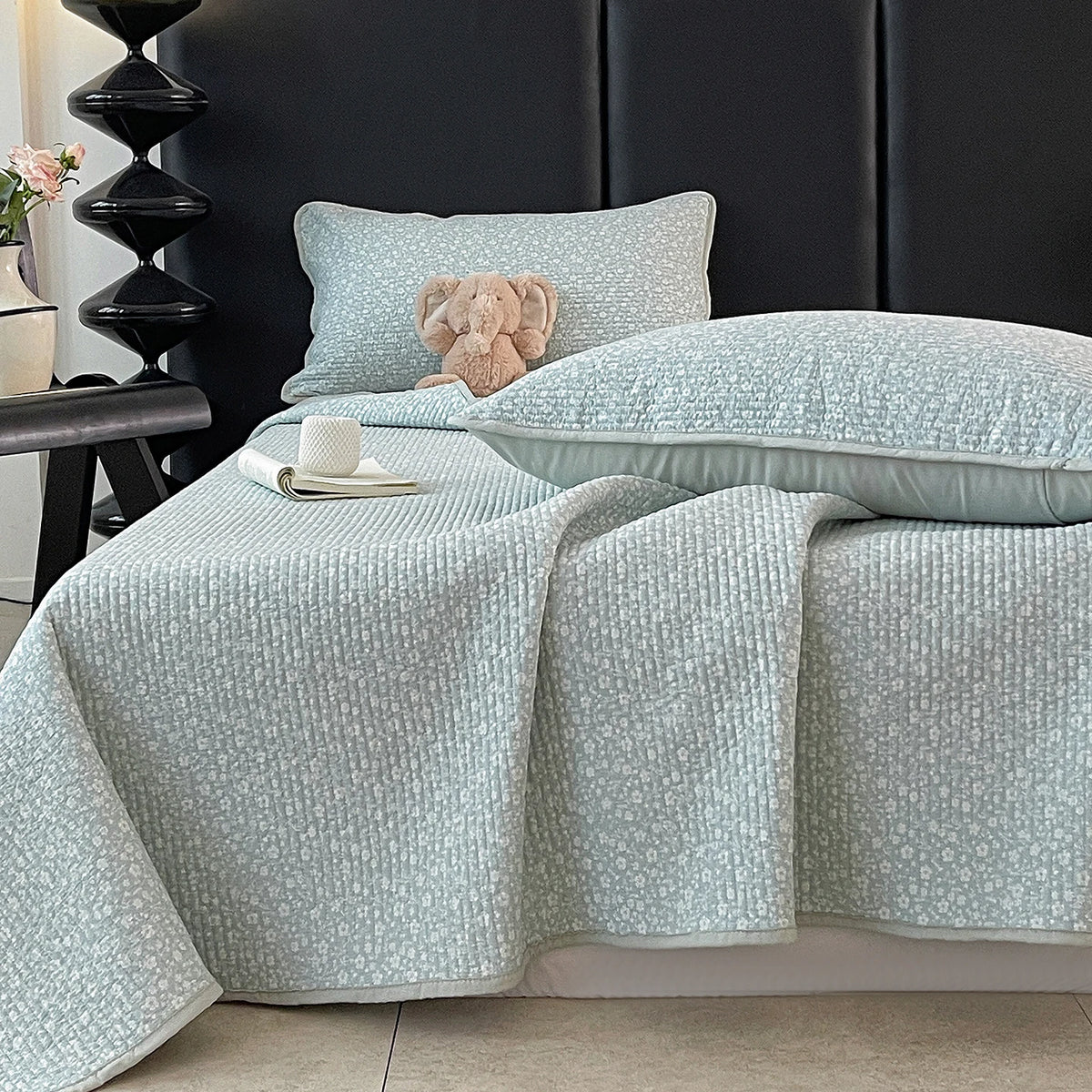 Light blue floral quilted bedspread with a fluffy pink toy resting on the bedding.
