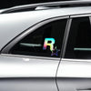 A close-up of a silver car window showing an iridescent R-Star vinyl sticker with a five-pointed star design.