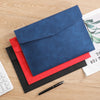 Un classeur de documents A4 en cuir PU bleu marine, avec un stylo rouge et noir, sur une surface en bois.