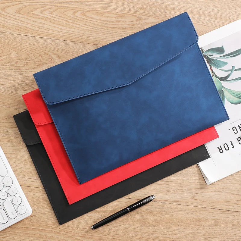 Un classeur de documents A4 en cuir PU bleu marine, avec un stylo rouge et noir, sur une surface en bois.