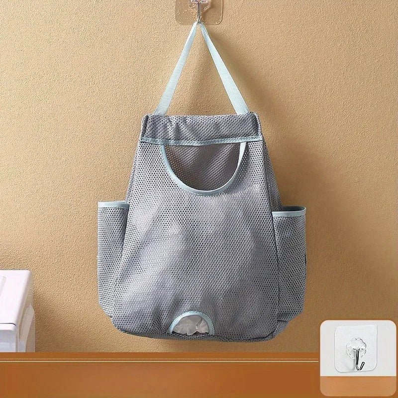 A gray mesh garbage bag holder is mounted on a wall with hooks, designed to keep bags accessible.