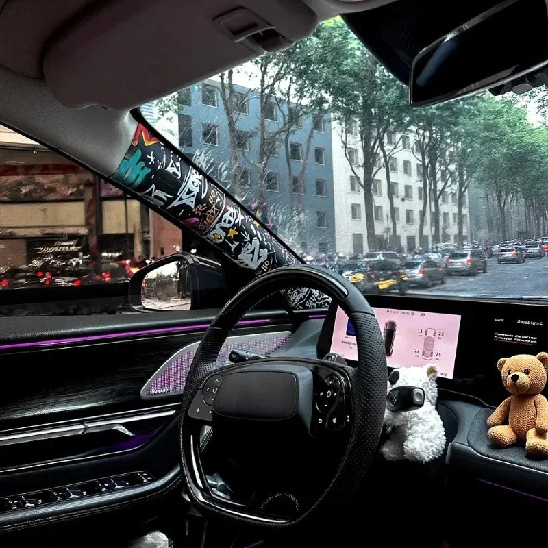 Interior view of a car showing a graffiti pattern velvet wrap sticker on the door and a steering wheel with a teddy bear keyc