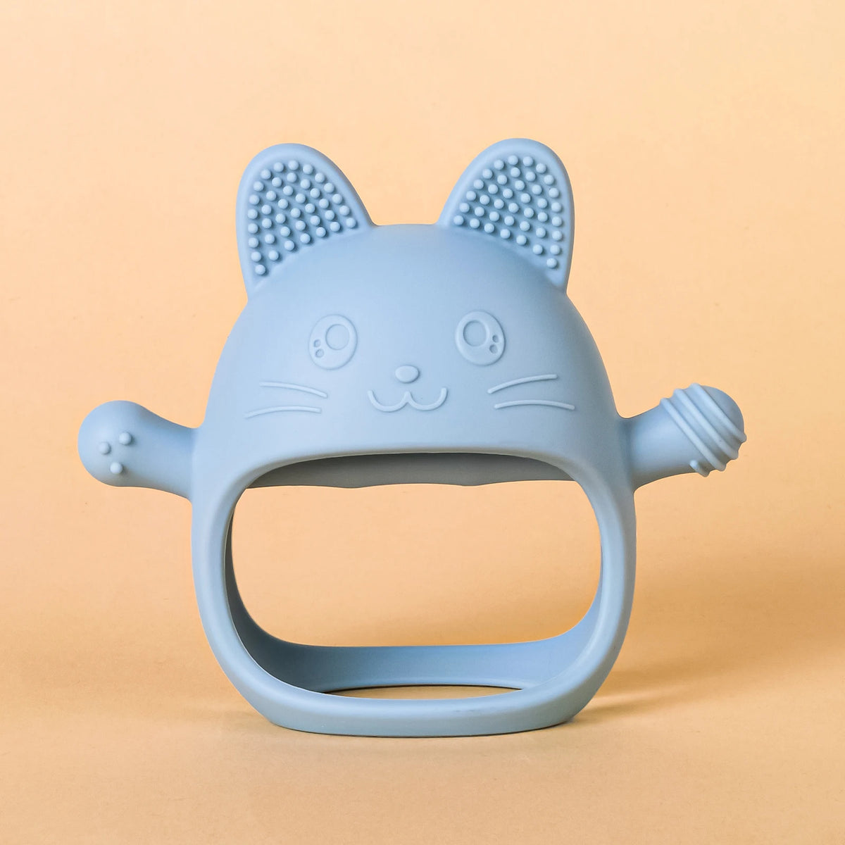 A light blue silicone cat-shaped teether for baby gums with textured ears and whiskers.