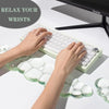 Hands are using a white cloud-shaped ergonomic wrist rest set for a keyboard and mouse on a white desk.