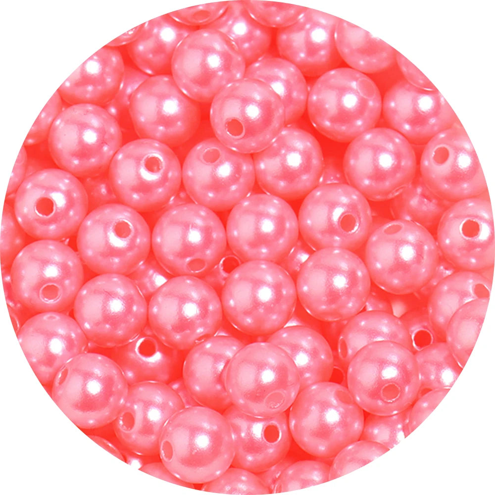 A close-up view of small, round, pink imitation pearl beads for jewelry making.