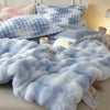 A light blue faux fur comforter with a blue and white plaid pattern is displayed on a bed.