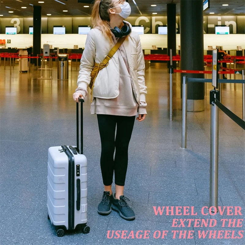 A person is standing in an airport terminal with a rolling suitcase on the floor.