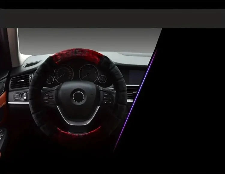 A close-up view of a steering wheel covered in a dark material with red accents, likely a plush cover.