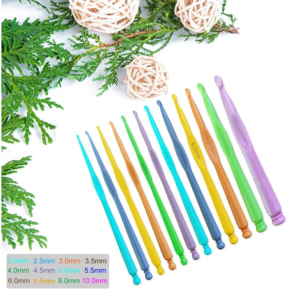 A set of twelve colorful plastic crochet hooks in various sizes ranging from 2.0mm to 10.0mm displayed on a green branch.