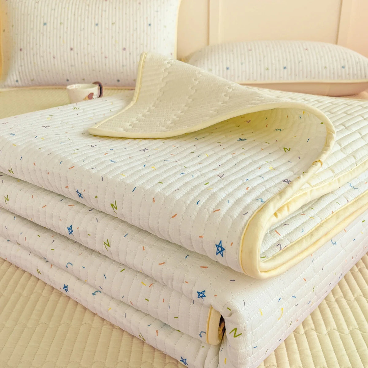 A stack of white floral quilted fabric covers or blankets resting on a light yellow surface.