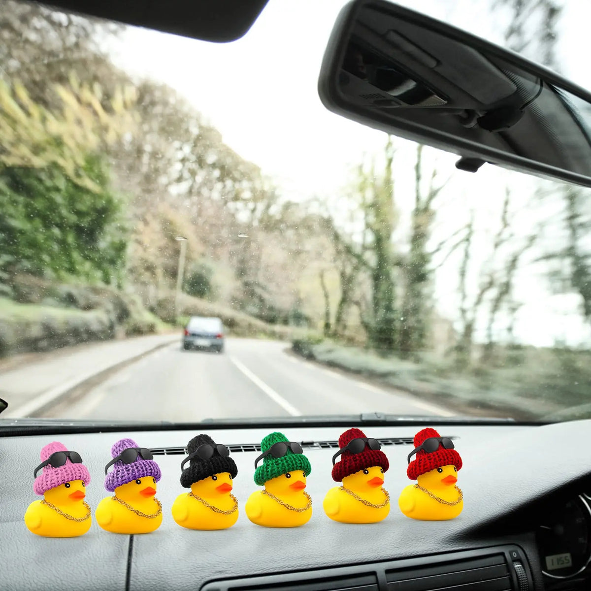 Yellow rubber duck car dashboard ornament with accessories on a car dashboard.