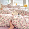 A light pink floral duvet cover set featuring a delicate pattern on a bed.