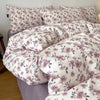 A set of soft printed duvet covers and pillowcases featuring a floral pattern in shades of mauve and green.
