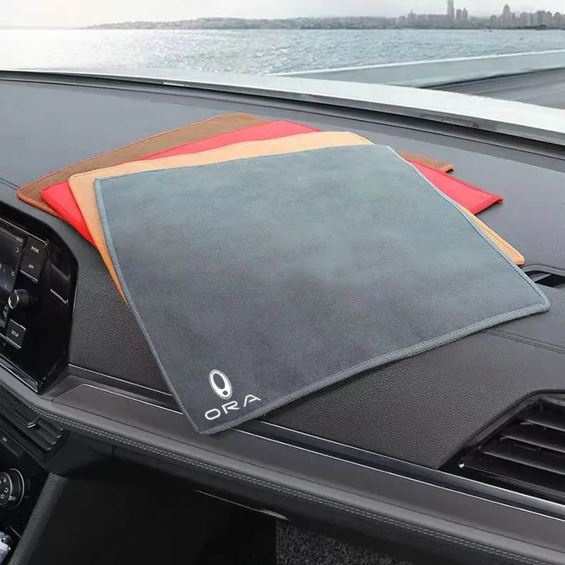 A stack of colored microfiber car drying towels rests on a dark car surface.