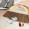 A wooden broom with bristles and a white handle is shown next to a piece of crumpled white paper.