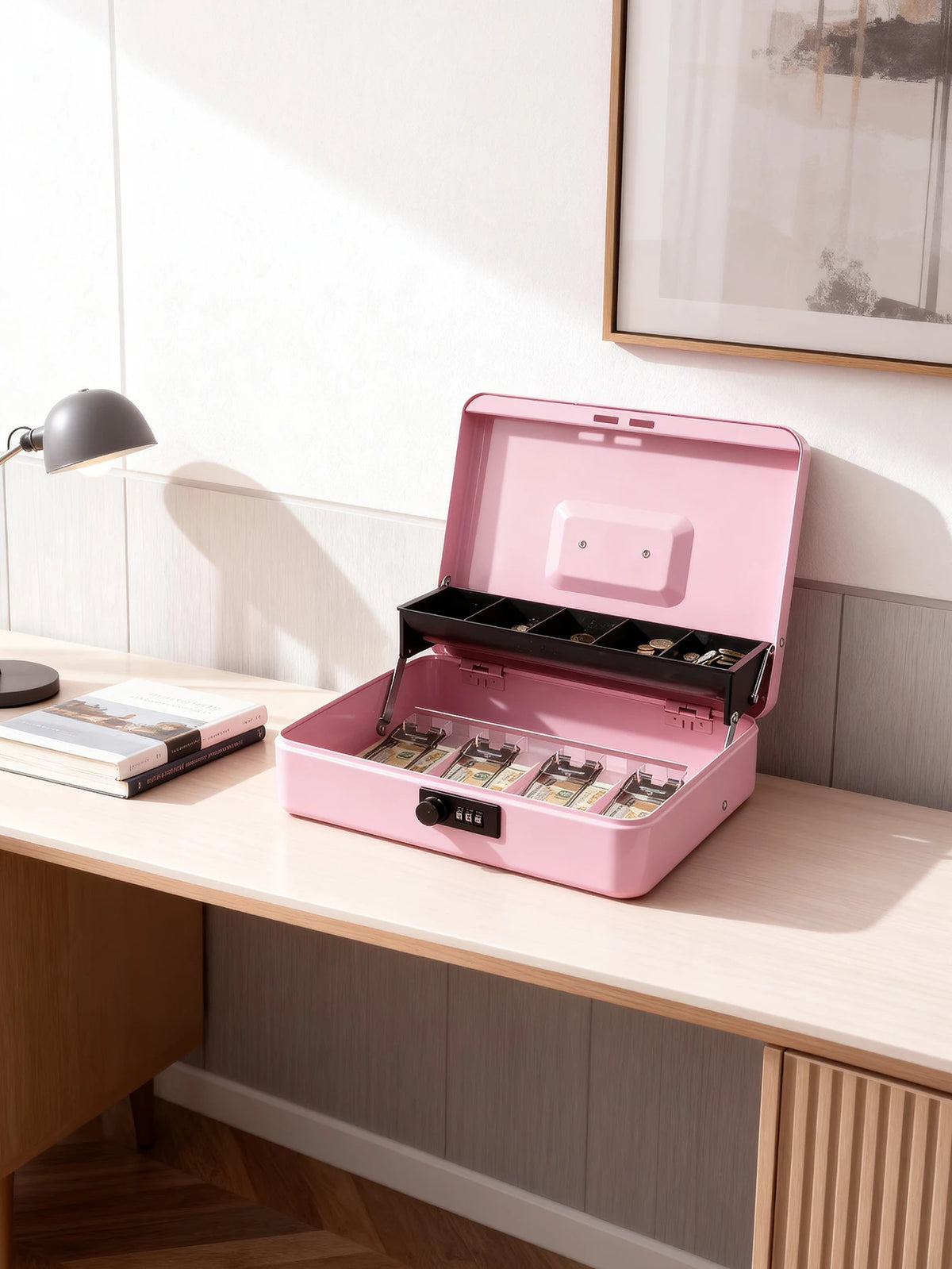 A pink lockable cash box with an open lid displaying coin trays and money inside on a wooden desk.