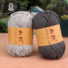 Two skeins of gray cotton blend crochet yarn are displayed on a wooden surface.