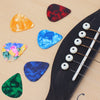 A collection of colorful celluloid guitar picks arranged on a wooden surface next to an acoustic guitar neck.