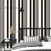 A bedroom setting featuring black and white striped wallpaper, a dark light fixture, and bedding.