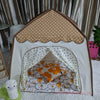 A beige and white foldable kids teepee play tent with a scalloped roof and interior bedding.