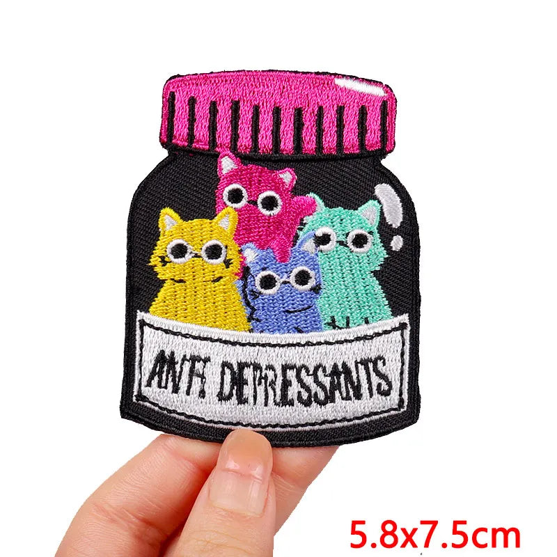A black embroidery patch featuring cartoon cats in various colors, including pink, yellow, purple, and green.