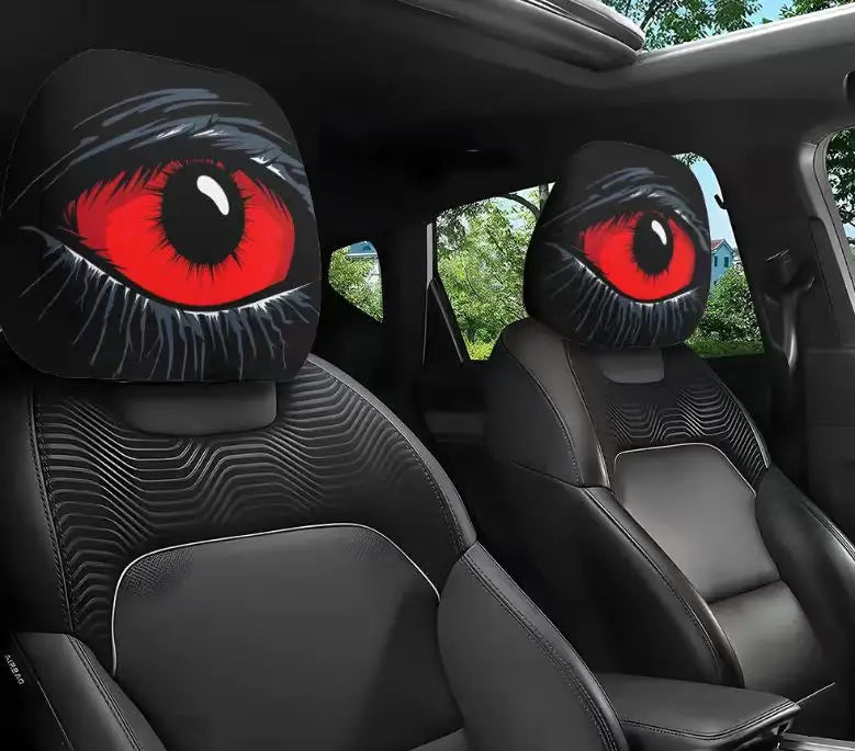 A pair of black and red cartoon eye headrest covers for car seats shown inside a vehicle.