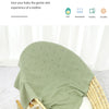 A light green knit swaddle blanket is draped over a woven basket, suggesting a gentle sleep companion for a baby.