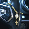 A gold chain rosary with a cross pendant is draped across the steering wheel of a car.